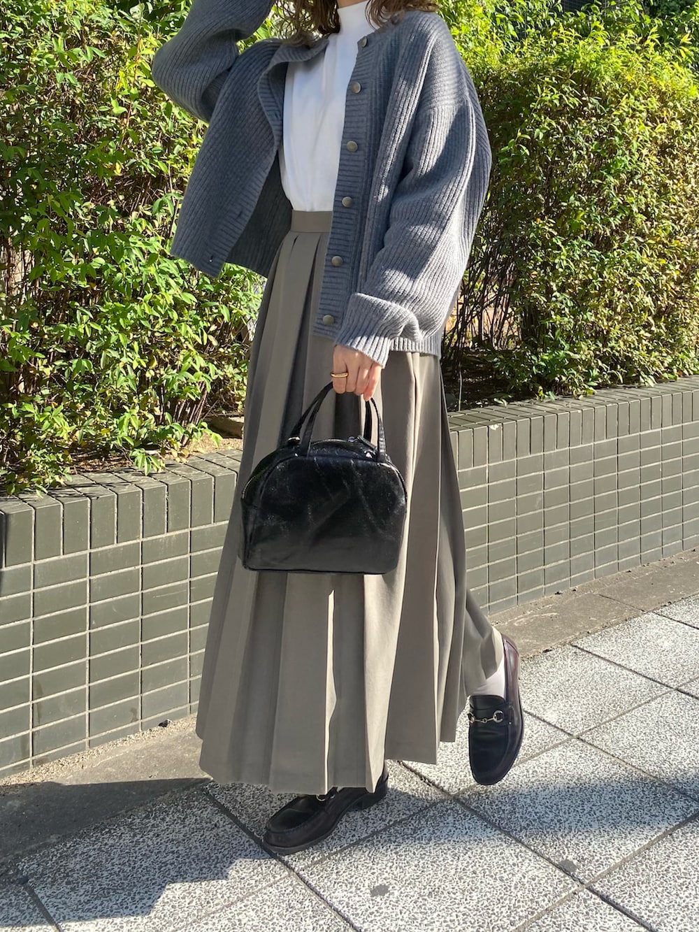 ブラウン系のローファー、ブラック系のショルダーバッグ、グリーン系のスカートを着用したレディースの秋コーディネートの3枚目の写真