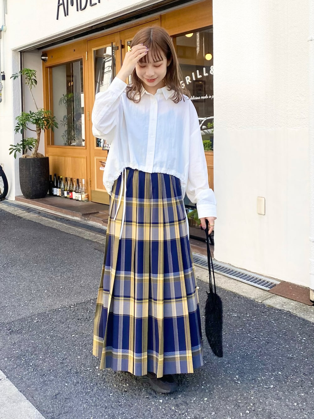 ブルー系のスカート、ホワイト系のシャツ/ブラウス、ブラック系のショルダーバッグを着用したレディースの秋コーディネートの2枚目の写真