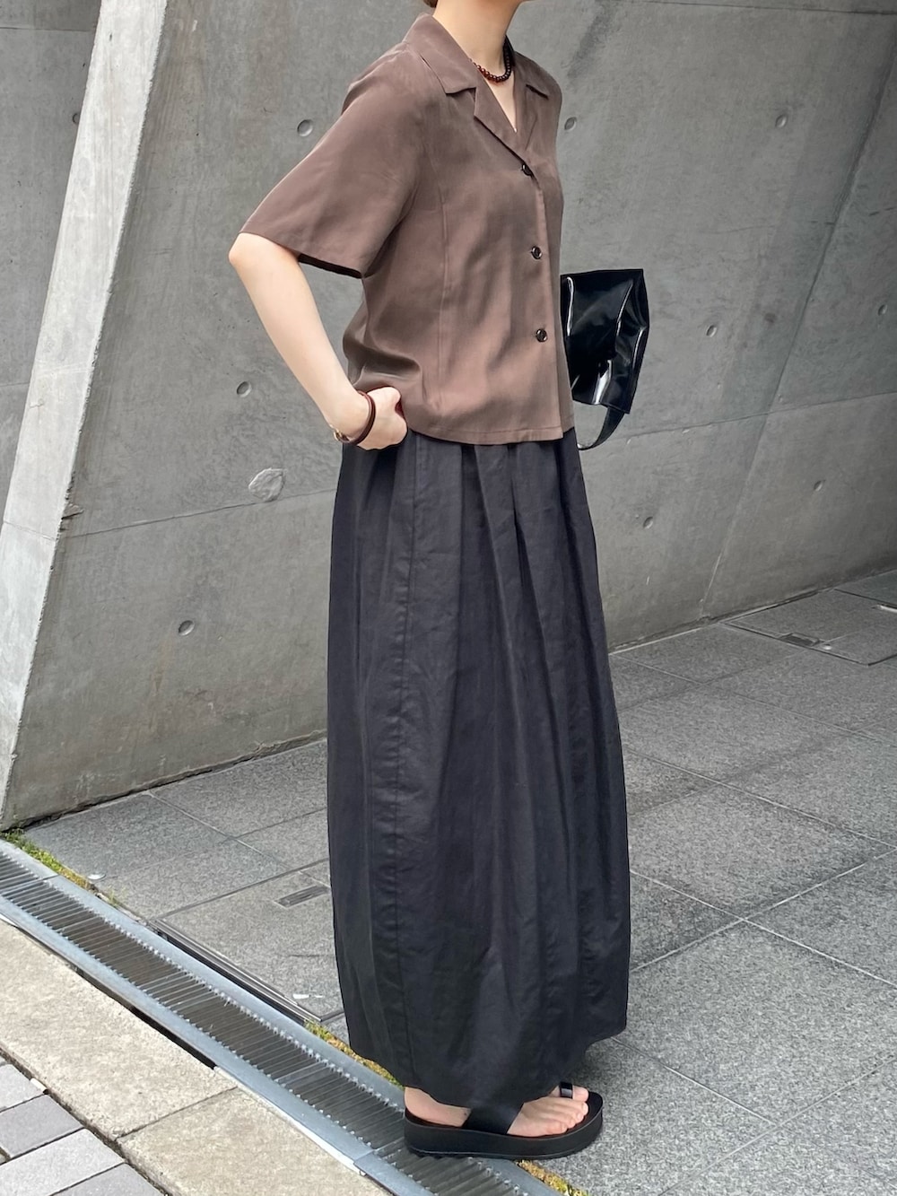 ブラック系のスカート、ブラウン系のシャツ/ブラウス、ブラック系のサンダルを着用したレディースの夏コーディネートの3枚目の写真