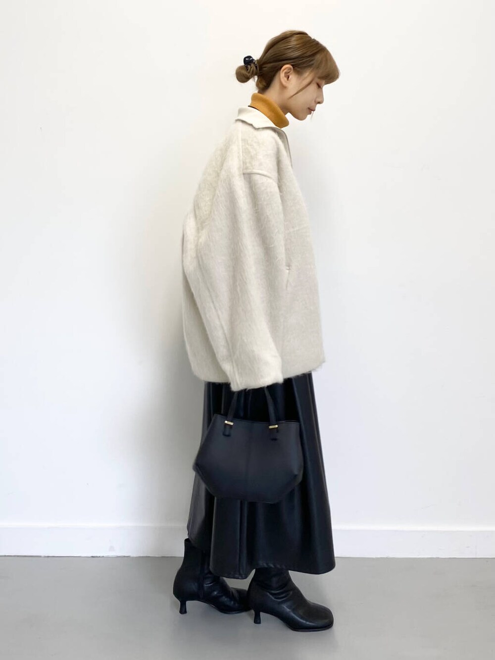 イエロー系のニット/セーター、ブラック系のショルダーバッグ、ブラック系のブーツを着用したレディースの冬コーディネートの8枚目の写真