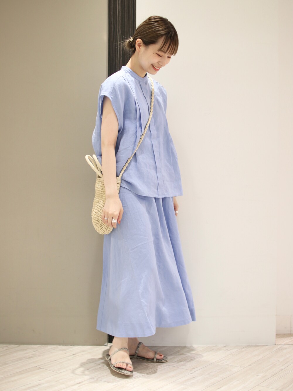 グレー系のサンダル、ブルー系のスカート、ベージュ系のショルダーバッグを着用したレディースの夏コーディネートの2枚目の写真