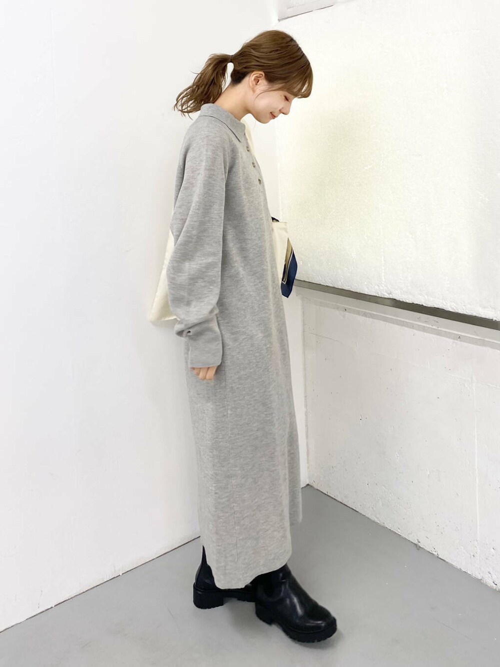 ブラック系のブーツ、ホワイト系のトートバッグ、グレー系のワンピースを着用したレディースの秋コーディネートの4枚目の写真