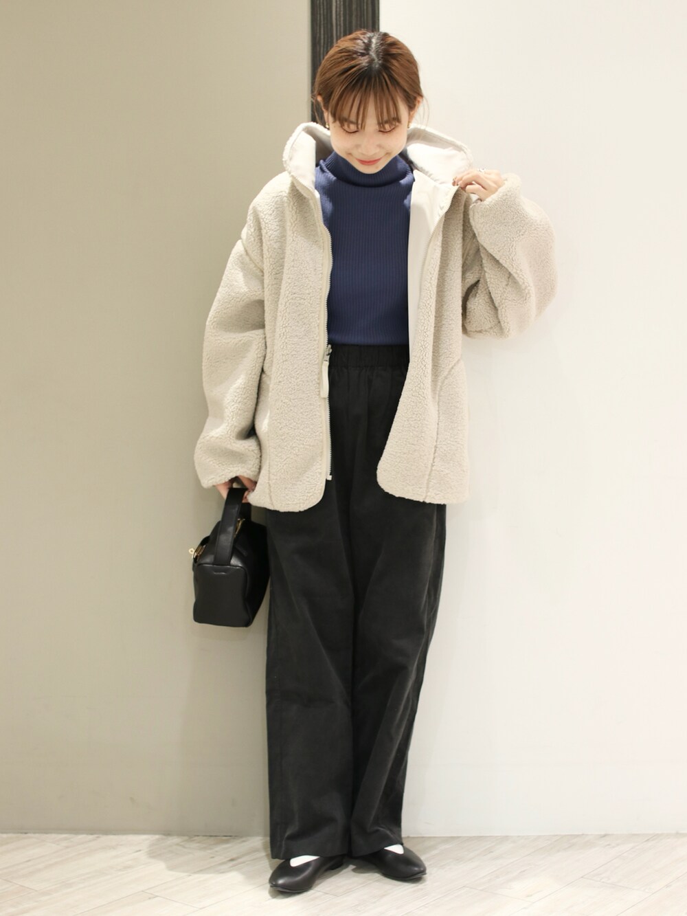 グレー系のその他パンツ、ブルー系のニット/セーター、ホワイト系のブルゾンを着用したレディースの冬コーディネートの3枚目の写真