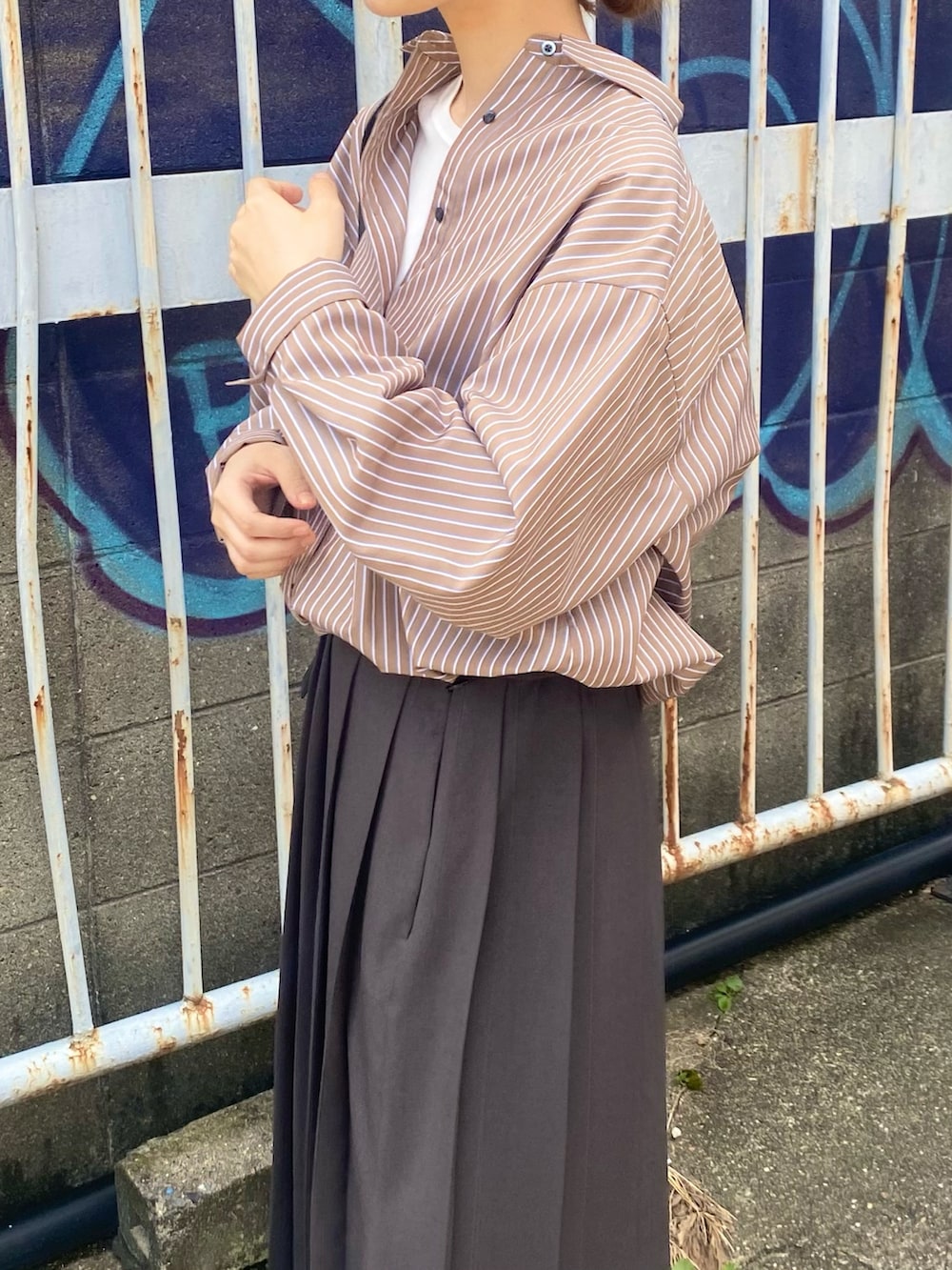 グレー系のスカート、ブラウン系のシャツ/ブラウス、ブラック系のローファーを着用したレディースの秋コーディネートの2枚目の写真