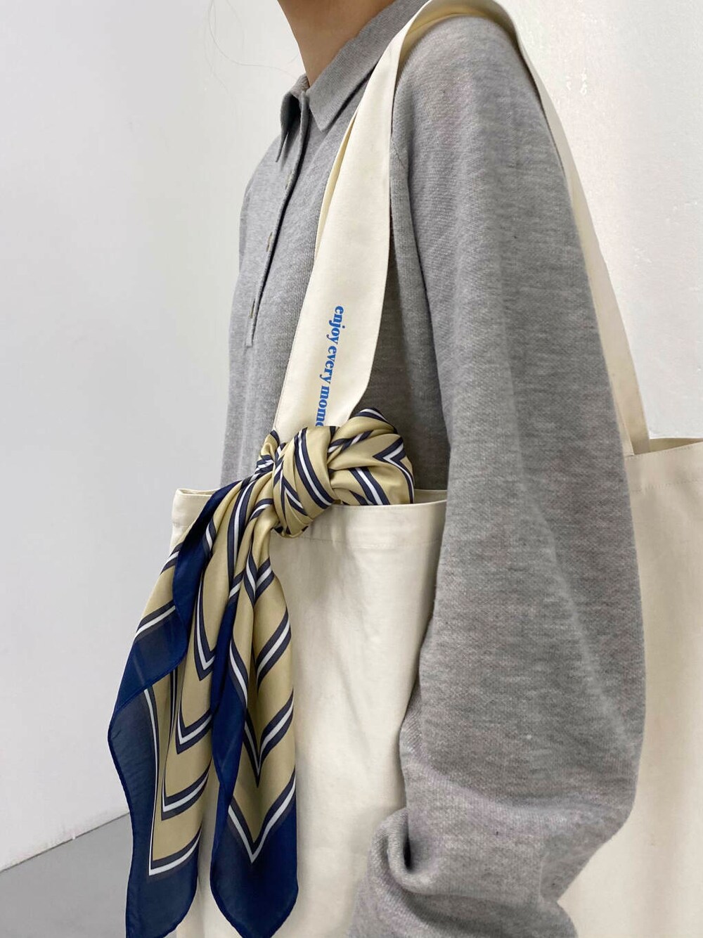 ブラック系のブーツ、ホワイト系のトートバッグ、グレー系のワンピースを着用したレディースの秋コーディネートの8枚目の写真