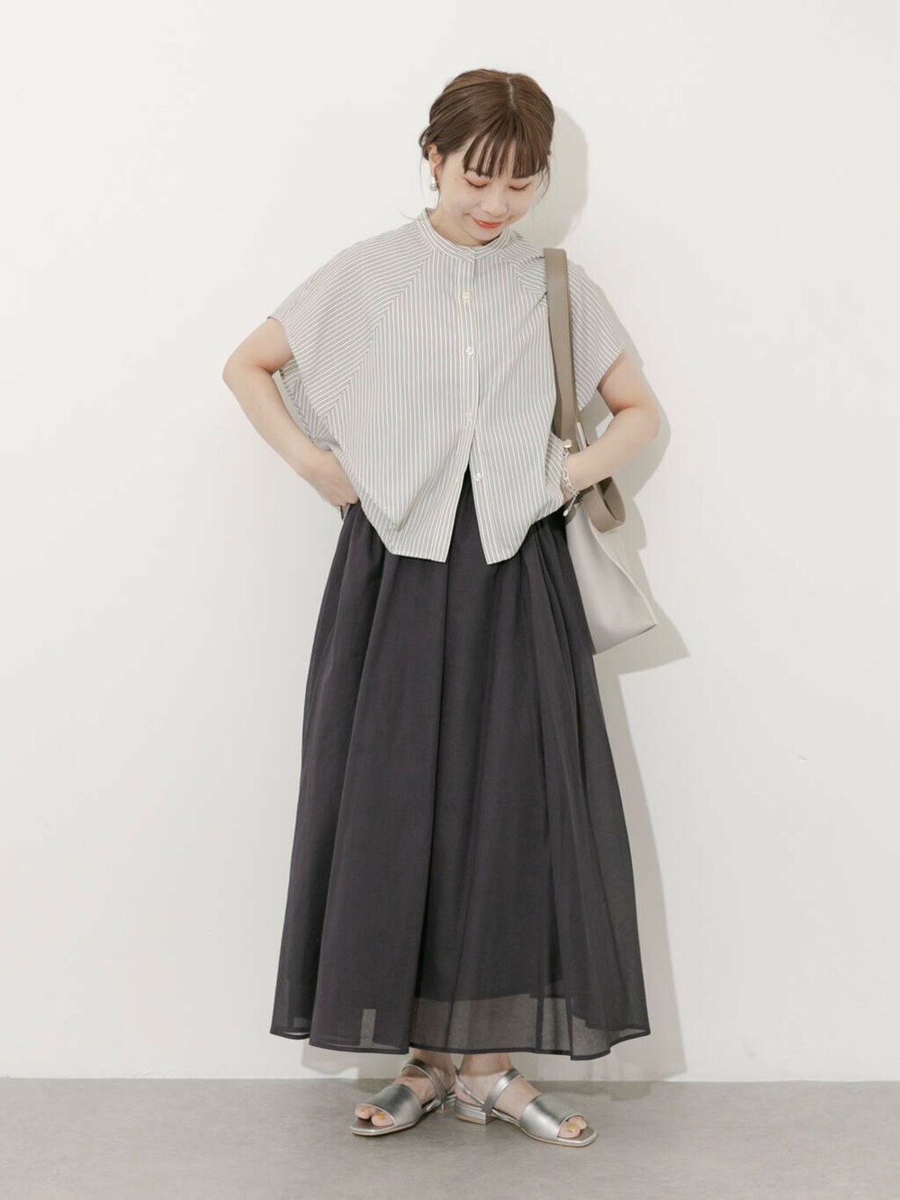 グレー系のスカート、ホワイト系のシャツ/ブラウス、シルバー系のサンダルを着用したレディースの夏コーディネートの2枚目の写真