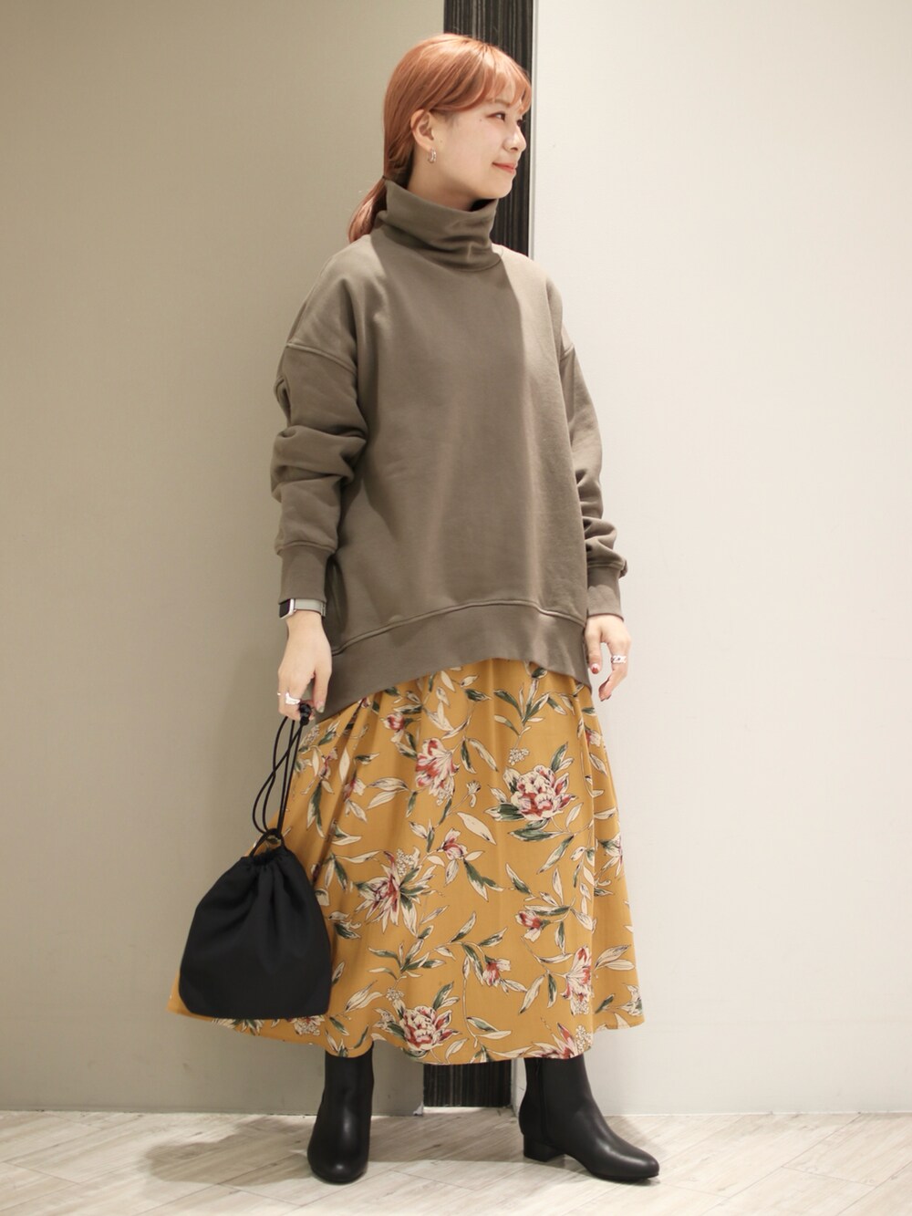 グリーン系のスウェット、オレンジ系のスカート、ブラック系のショルダーバッグを着用したレディースの秋コーディネートの2枚目の写真