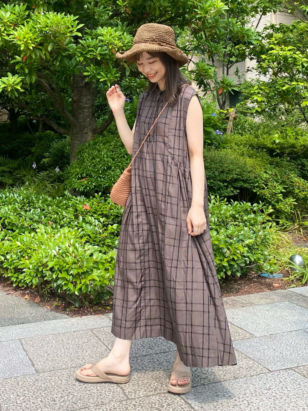 ベージュ系のかごバッグ、ブラウン系のワンピース、ベージュ系のサンダルを着用したレディースの夏コーディネートの3枚目の写真