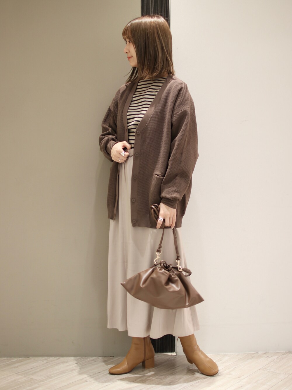 ブラウン系のカーディガン/ボレロ、ブラック系のTシャツ/カットソー、グレー系のスカートを着用したレディースの冬コーディネートの2枚目の写真