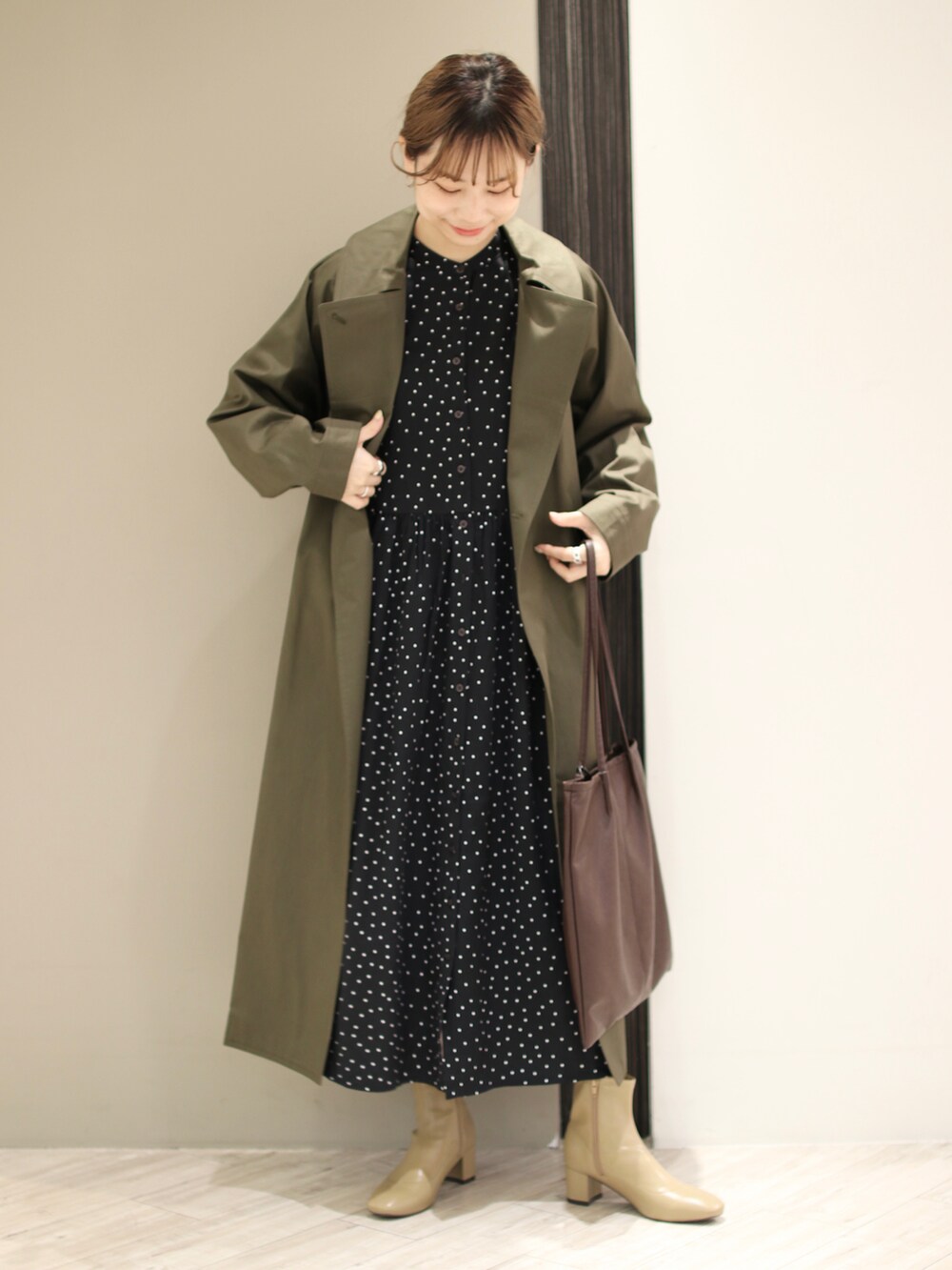 ブラウン系のトートバッグ、ベージュ系のブーツ、ブラック系のワンピースを着用したレディースの冬コーディネートの2枚目の写真