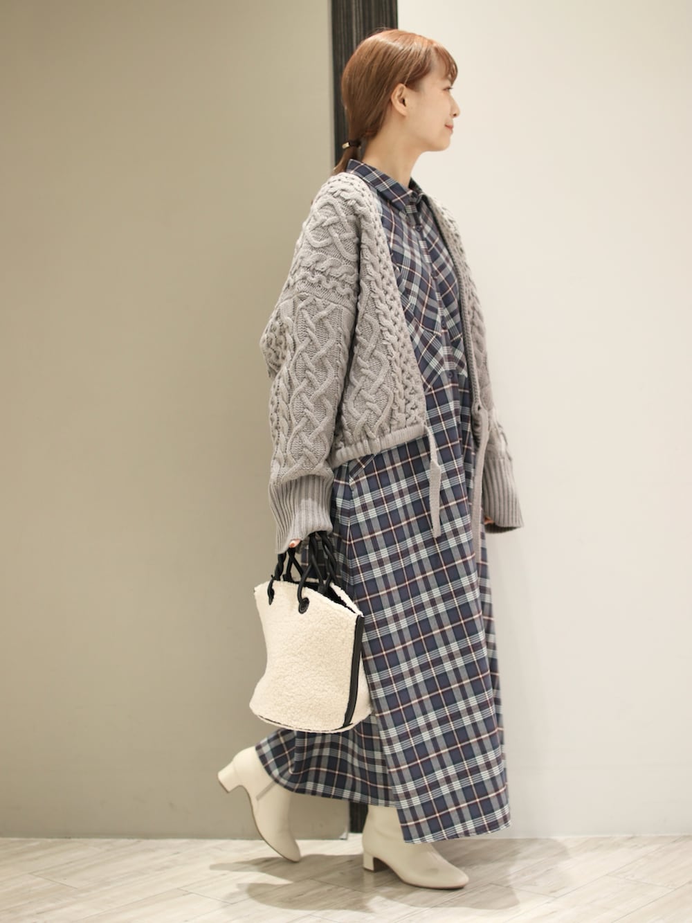 ホワイト系のハンドバッグ、グレー系のワンピース、グレー系のニット/セーターを着用したレディースの秋コーディネートの3枚目の写真