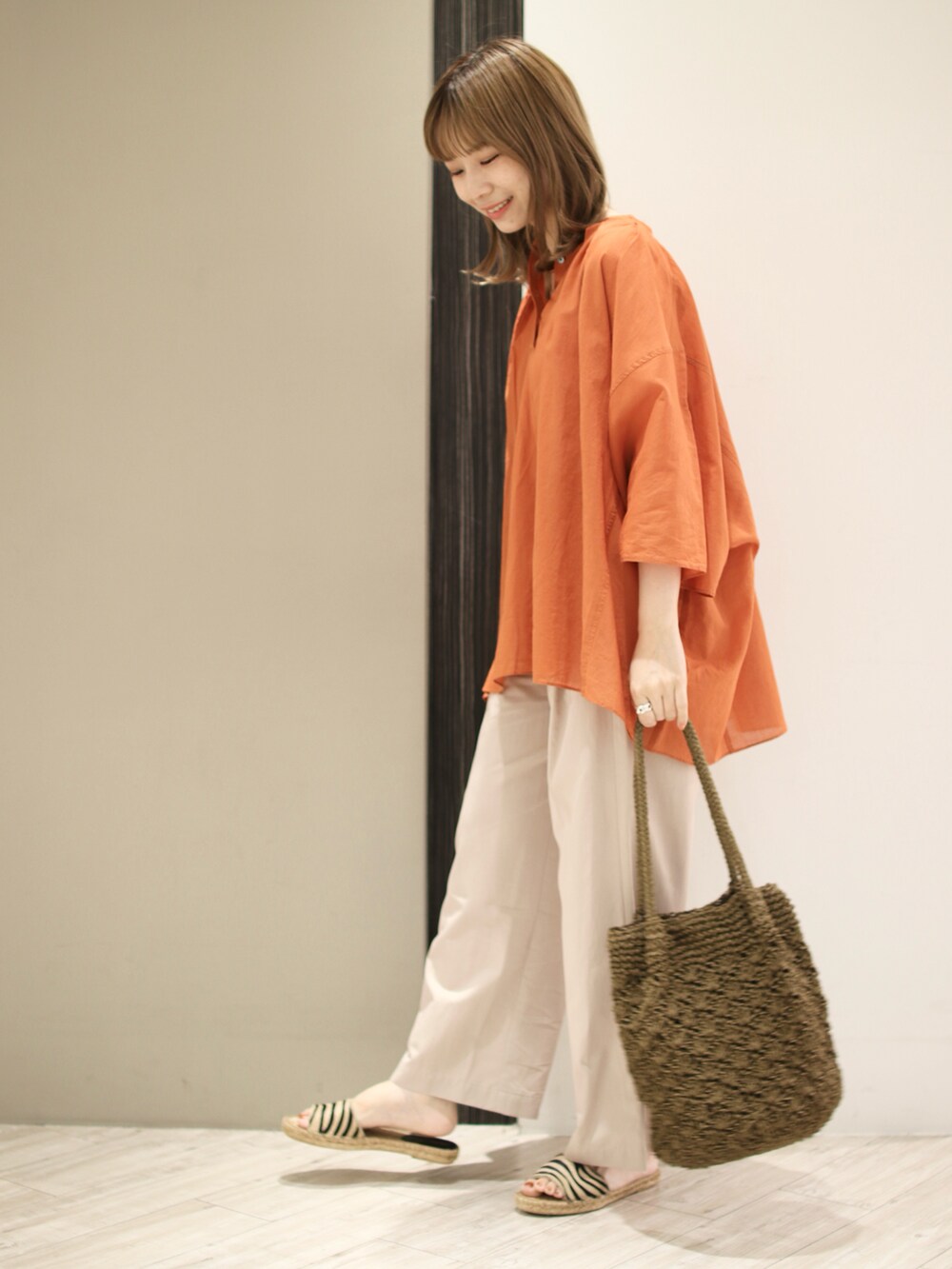 オレンジ系のシャツ/ブラウス、ベージュ系のその他パンツ、グリーン系のトートバッグを着用したレディースの夏コーディネートの2枚目の写真