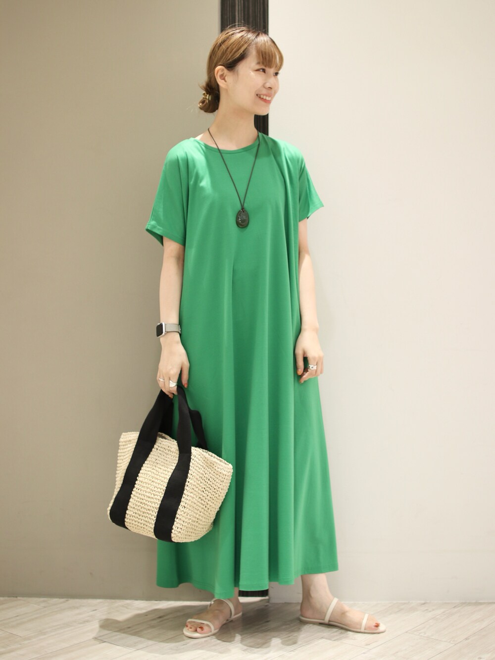 ベージュ系のトートバッグ、ホワイト系のサンダル、グリーン系のワンピースを着用したレディースの夏コーディネートの2枚目の写真