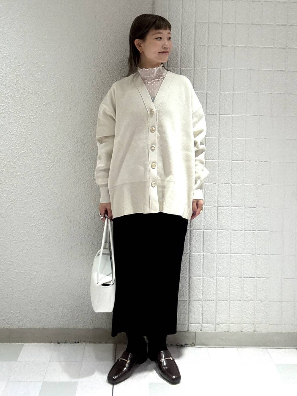 ホワイト系のカーディガン/ボレロ、ブラック系のスカート、ホワイト系のTシャツ/カットソーを着用したレディースの春コーディネートの2枚目の写真