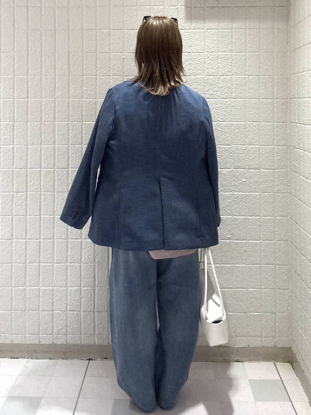 ブルー系のデニムパンツ、ピンク系のシャツ/ブラウス、ホワイト系のショルダーバッグを着用したレディースの春コーディネートの4枚目の写真