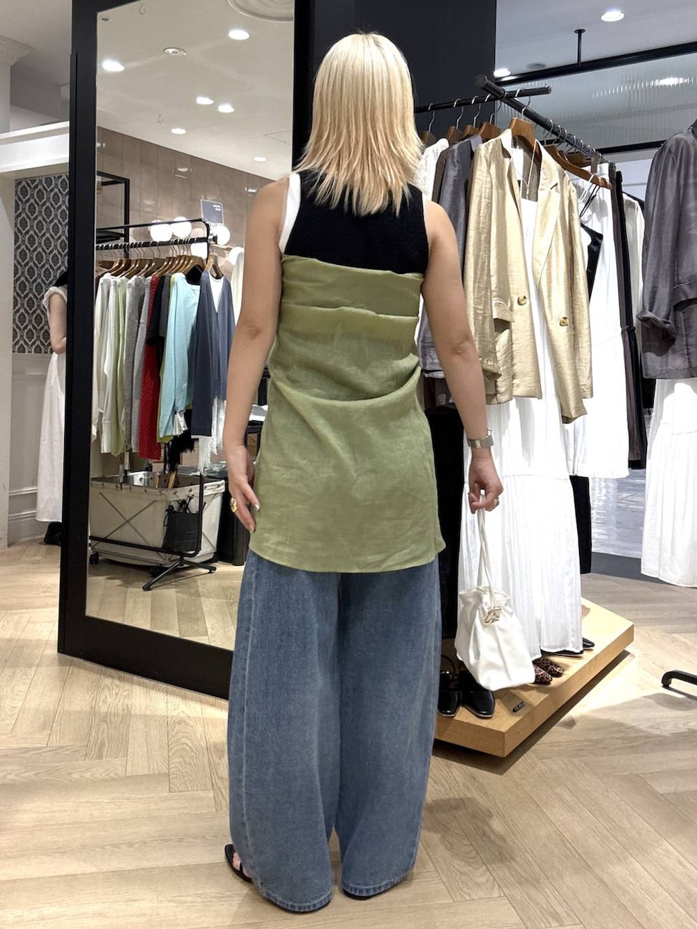ホワイト系のショルダーバッグ、ブルー系のデニムパンツ、ブラック系のサンダルを着用したレディースの夏コーディネートの5枚目の写真