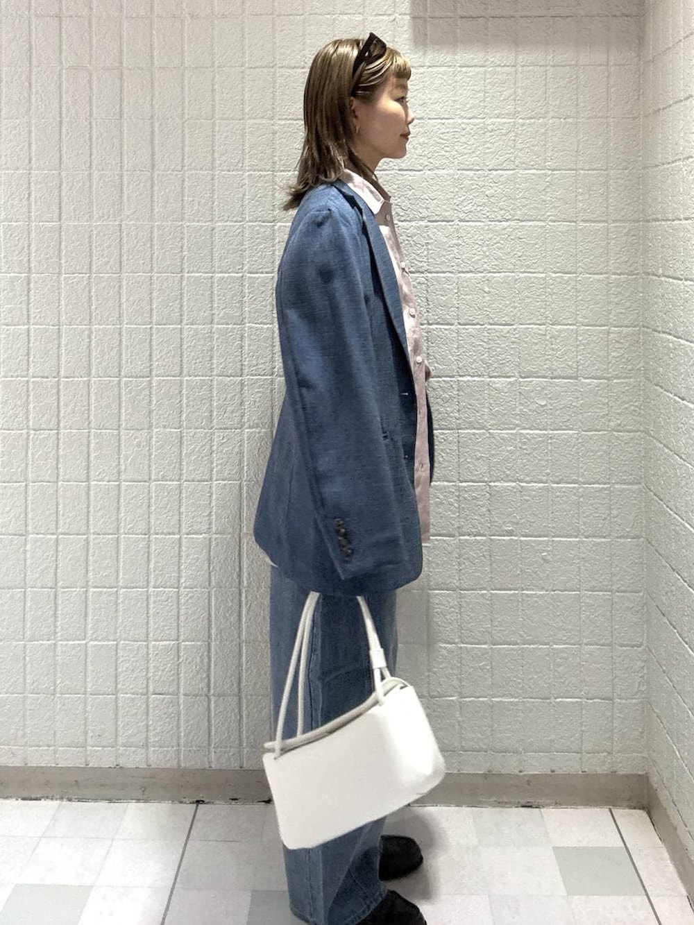 ブルー系のデニムパンツ、ピンク系のシャツ/ブラウス、ホワイト系のショルダーバッグを着用したレディースの春コーディネートの3枚目の写真