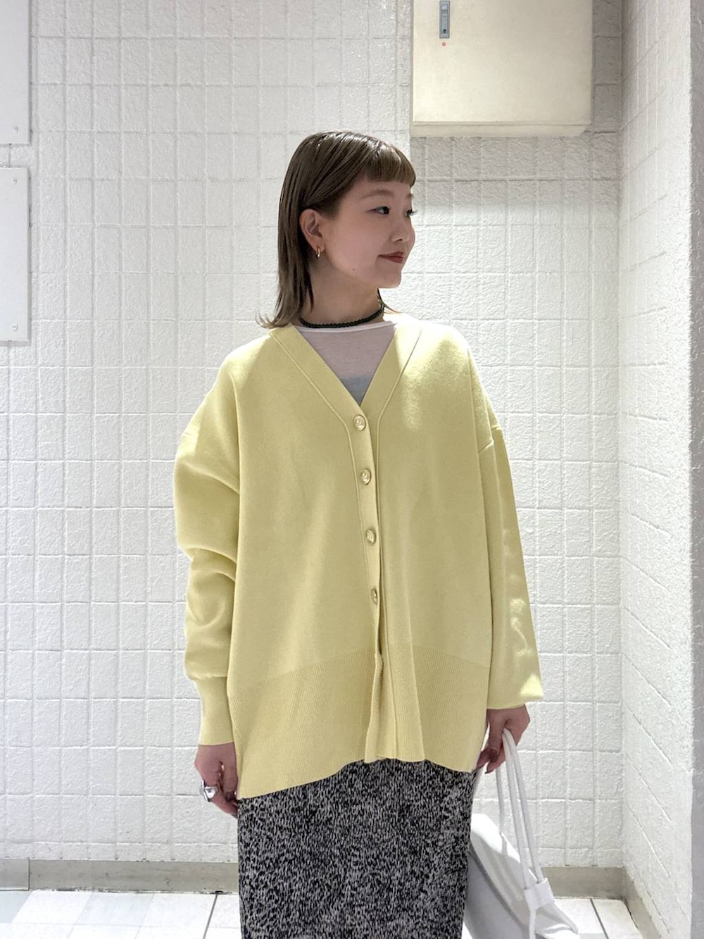 イエロー系のカーディガン/ボレロ、ブラウン系のスカート、ホワイト系のショルダーバッグを着用したレディースの春コーディネートの6枚目の写真