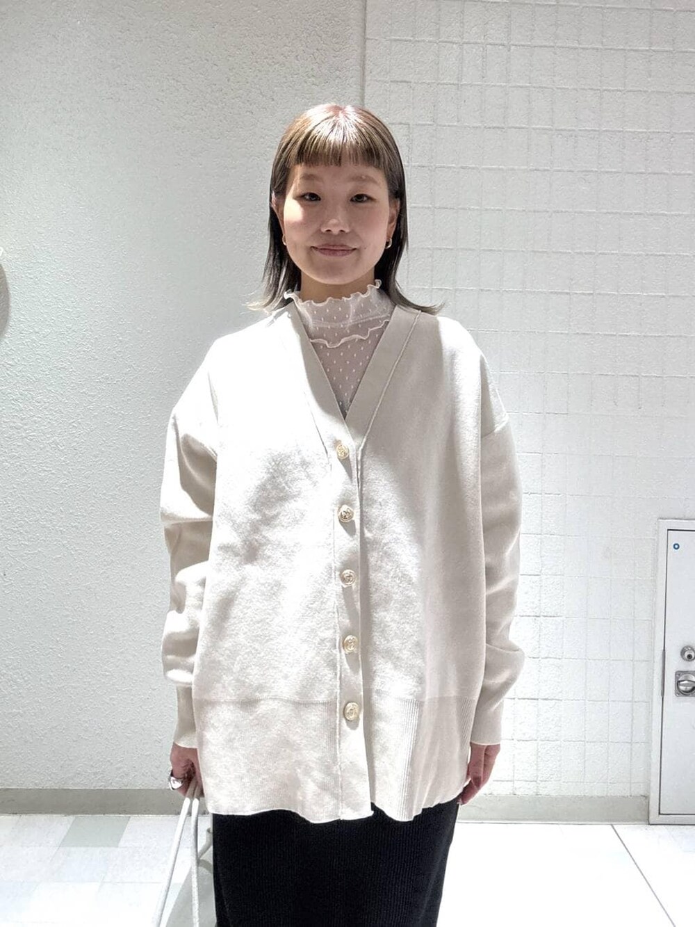 ホワイト系のカーディガン/ボレロ、ブラック系のスカート、ホワイト系のTシャツ/カットソーを着用したレディースの春コーディネートの6枚目の写真