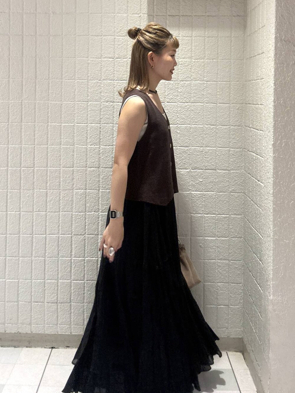 ベージュ系のショルダーバッグ、ブラウン系のベスト、レッド系のサンダルを着用したレディースの春コーディネートの3枚目の写真