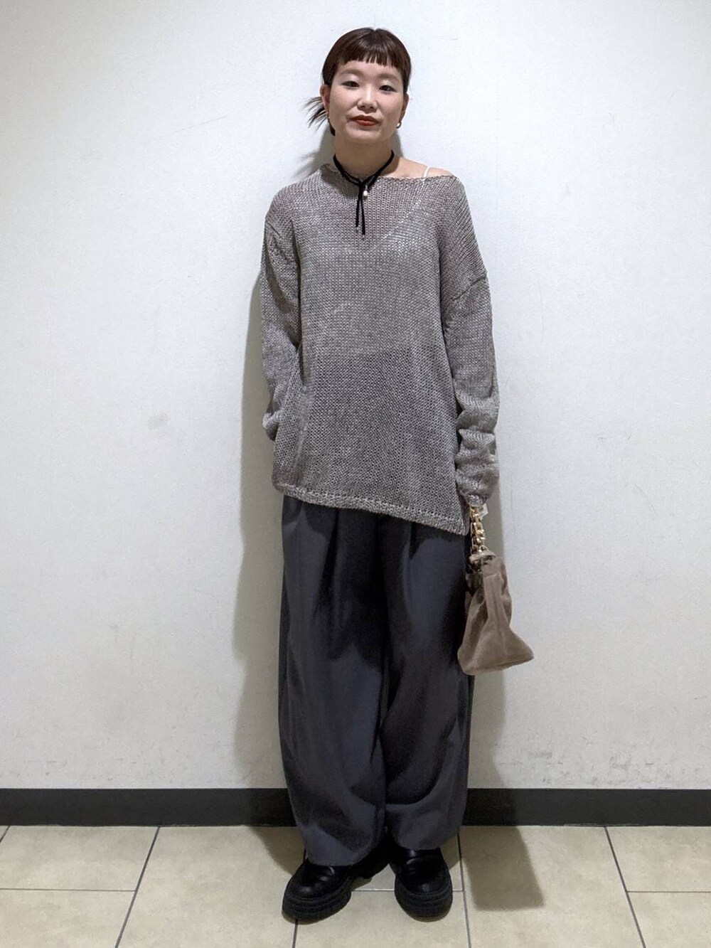 グレー系のスラックス、ベージュ系のショルダーバッグ、ホワイト系のキャミソールを着用したレディースの冬コーディネートの5枚目の写真