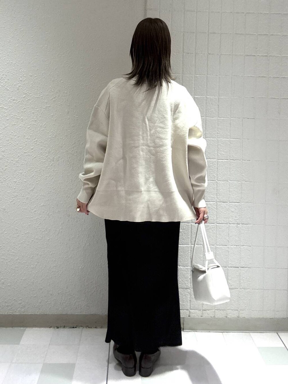 ホワイト系のカーディガン/ボレロ、ブラック系のスカート、ホワイト系のTシャツ/カットソーを着用したレディースの春コーディネートの4枚目の写真