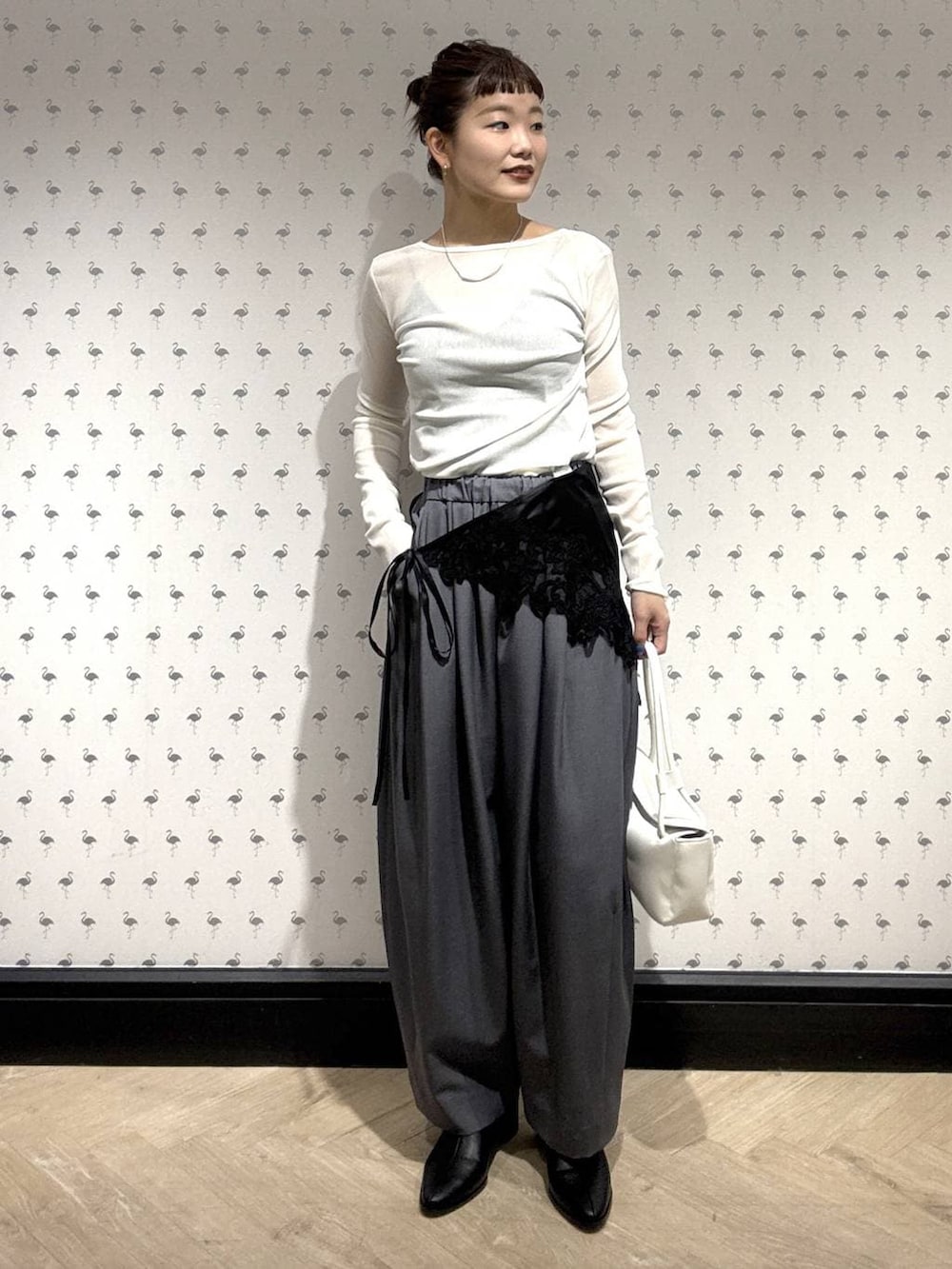 グレー系のスラックス、ホワイト系のTシャツ/カットソー、ブラック系のブーツを着用したレディースの冬コーディネートの2枚目の写真