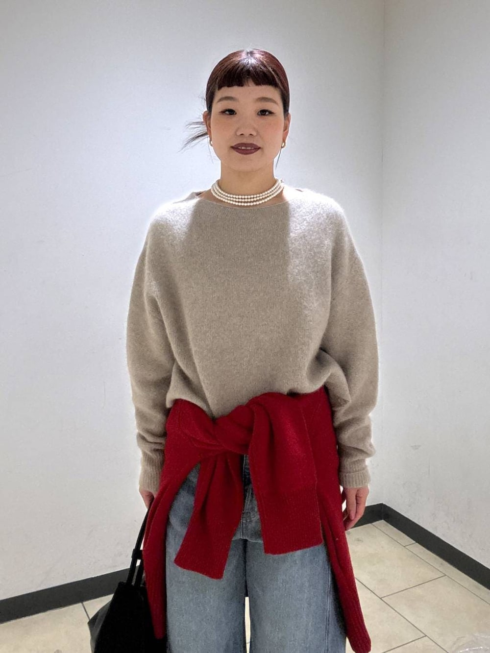 ベージュ系のニット/セーター、レッド系のカーディガン/ボレロ、ブルー系のデニムパンツを着用したレディースの冬コーディネートの6枚目の写真