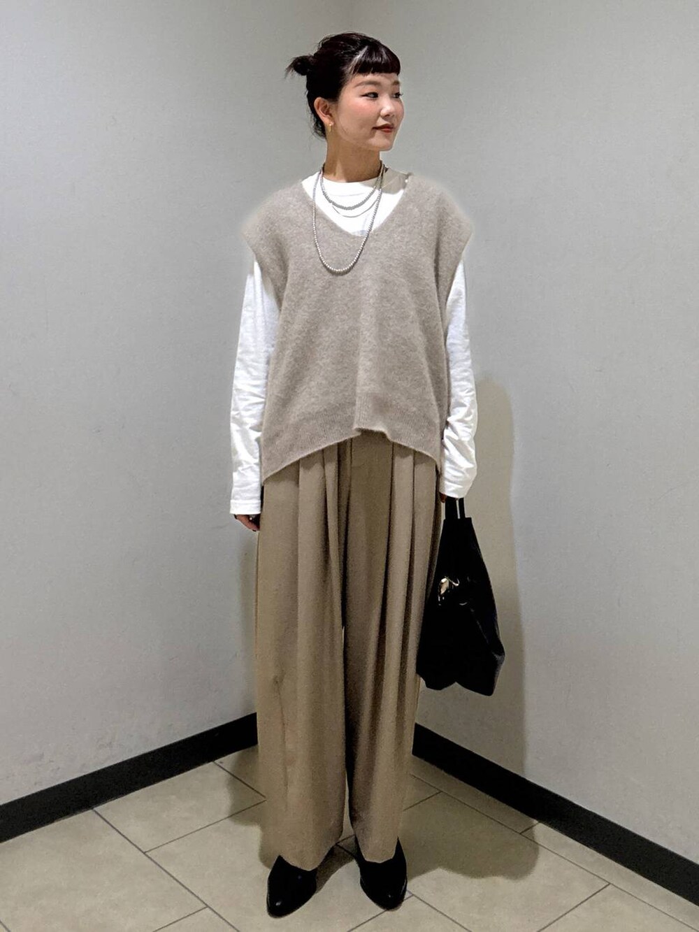 ベージュ系のスラックス、ブラック系のブーツ、ホワイト系のTシャツ/カットソーを着用したレディースの秋コーディネートの2枚目の写真