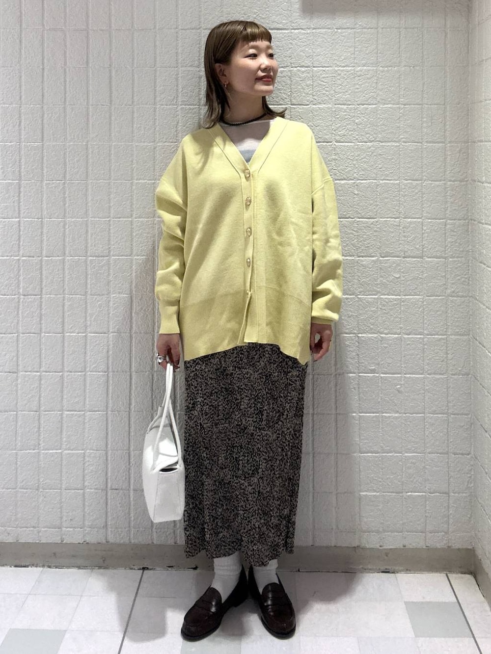イエロー系のカーディガン/ボレロ、ブラウン系のスカート、ホワイト系のショルダーバッグを着用したレディースの春コーディネートの2枚目の写真