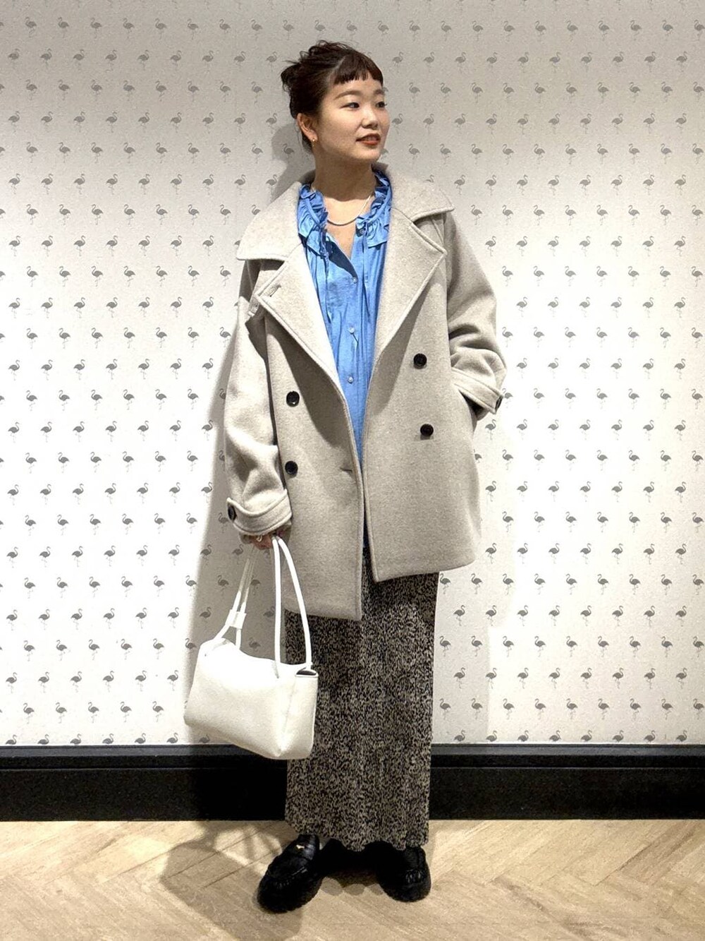 ベージュ系のピーコート、ブラウン系のスカート、ブラック系のローファーを着用したレディースの冬コーディネートの2枚目の写真