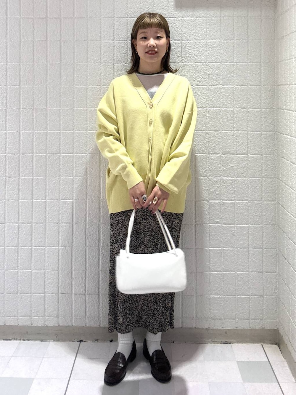 イエロー系のカーディガン/ボレロ、ブラウン系のスカート、ホワイト系のショルダーバッグを着用したレディースの春コーディネートの5枚目の写真