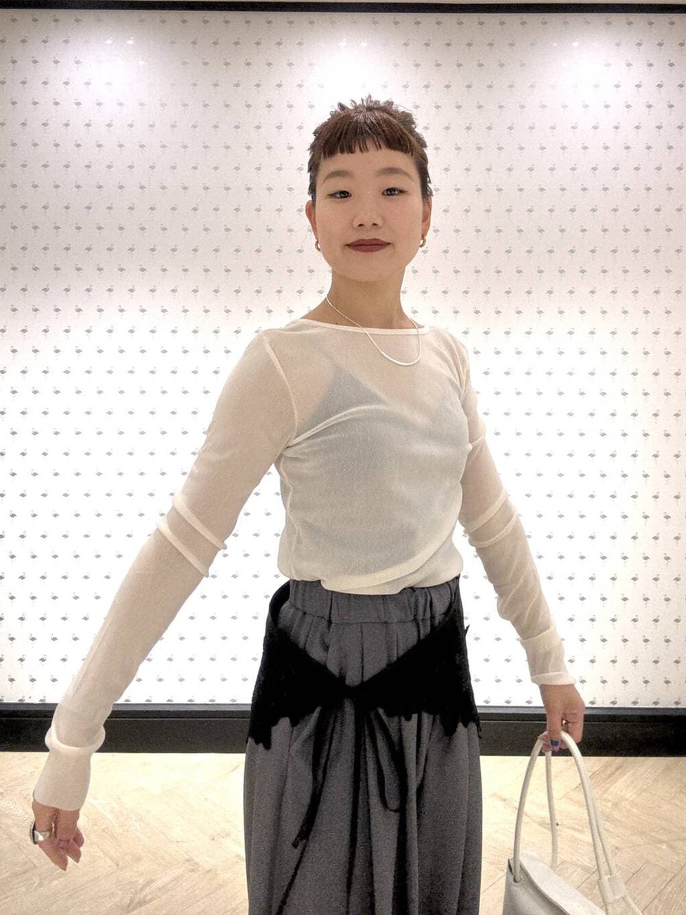 グレー系のスラックス、ホワイト系のTシャツ/カットソー、ブラック系のブーツを着用したレディースの冬コーディネートの6枚目の写真