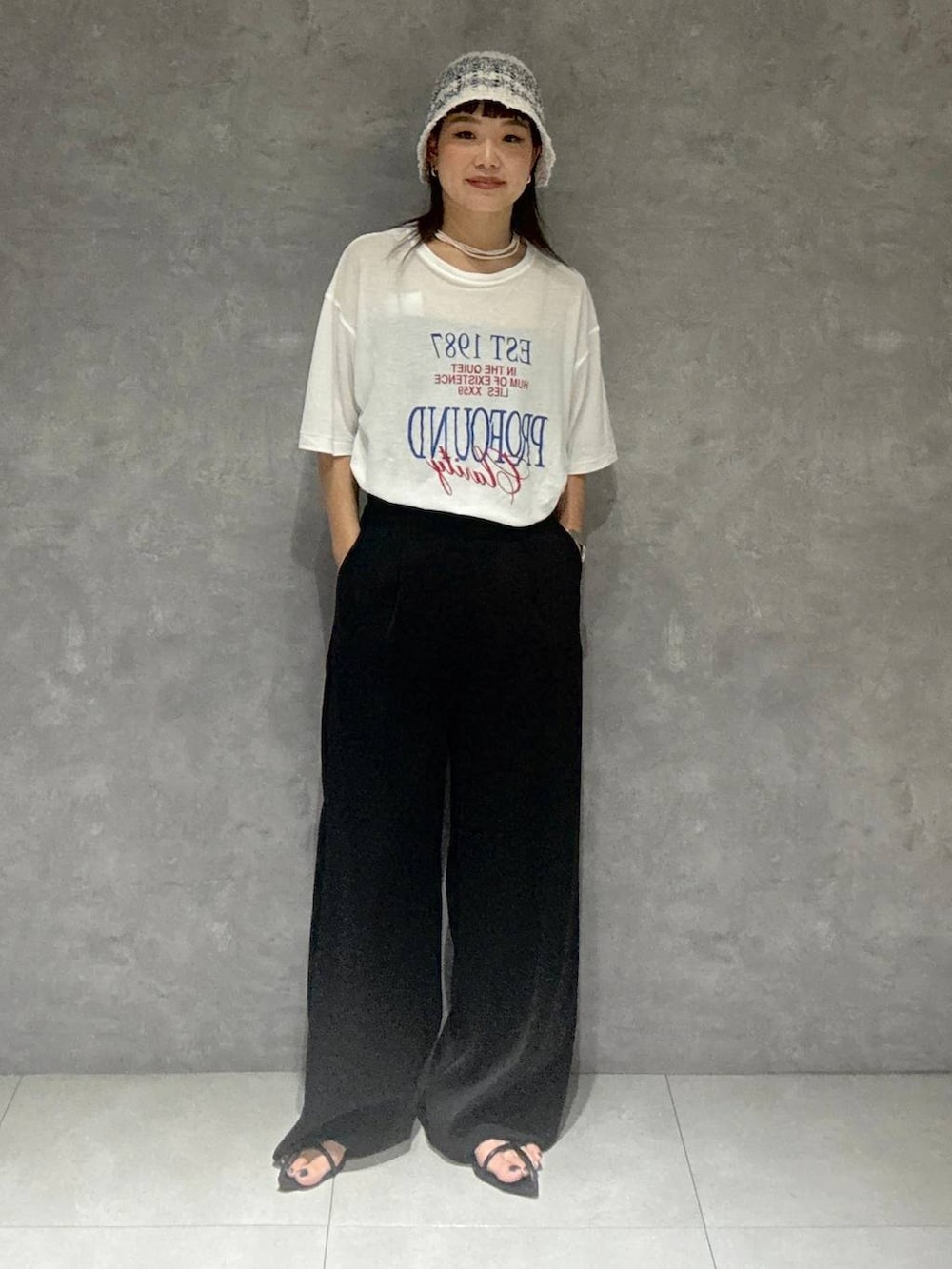 ブラック系のサンダル、ブラック系のスラックス、ホワイト系のTシャツ/カットソーを着用したレディースの夏コーディネートの4枚目の写真