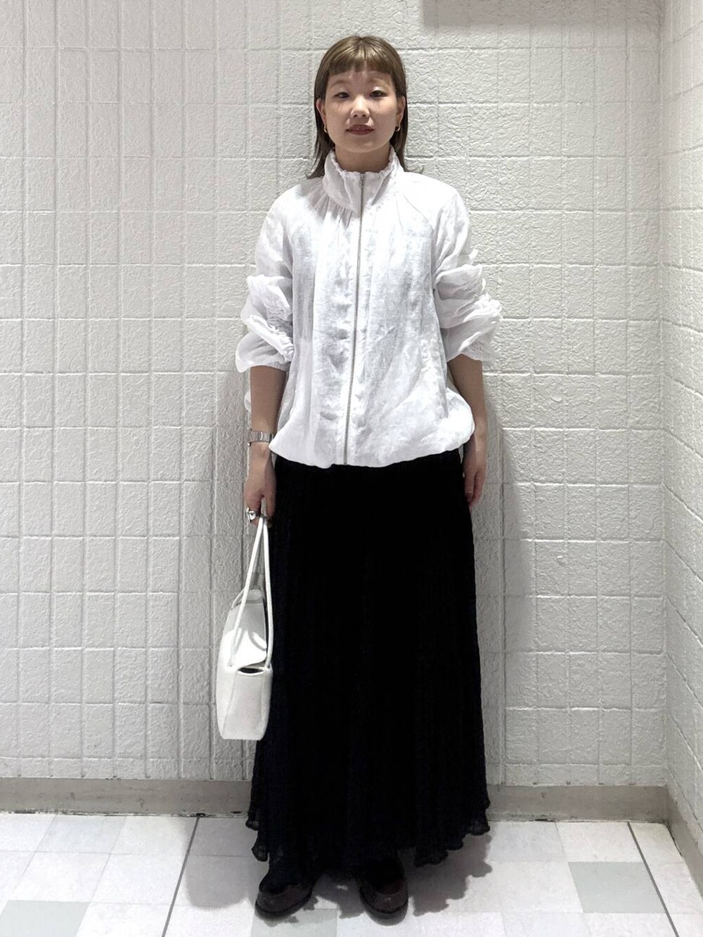 ホワイト系のショルダーバッグ、ホワイト系のブルゾン、ブラック系のワンピースを着用したレディースの春コーディネートの2枚目の写真