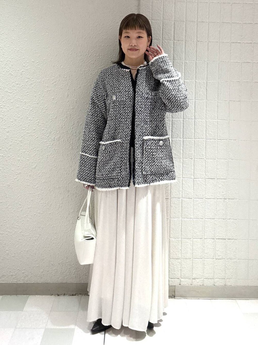 ホワイト系のスカート、ブラック系のノーカラージャケット、ホワイト系のショルダーバッグを着用したレディースの春コーディネートの5枚目の写真