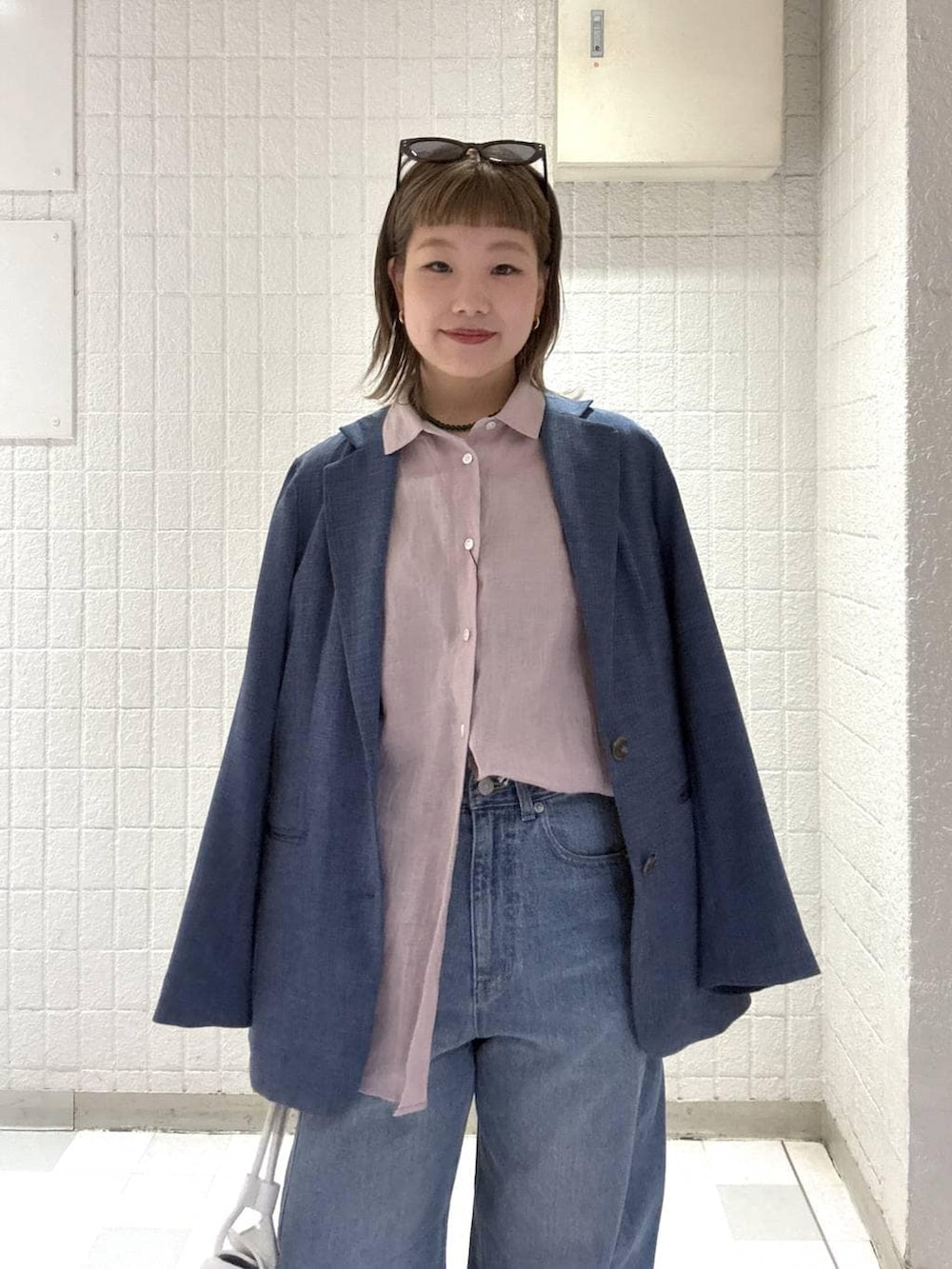 ブルー系のデニムパンツ、ピンク系のシャツ/ブラウス、ホワイト系のショルダーバッグを着用したレディースの春コーディネートの6枚目の写真