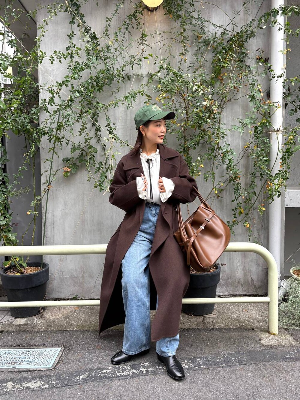 ブラウン系のステンカラーコート、ブルー系のデニムパンツ、ホワイト系のシャツ/ブラウスを着用したレディースの秋コーディネートの4枚目の写真