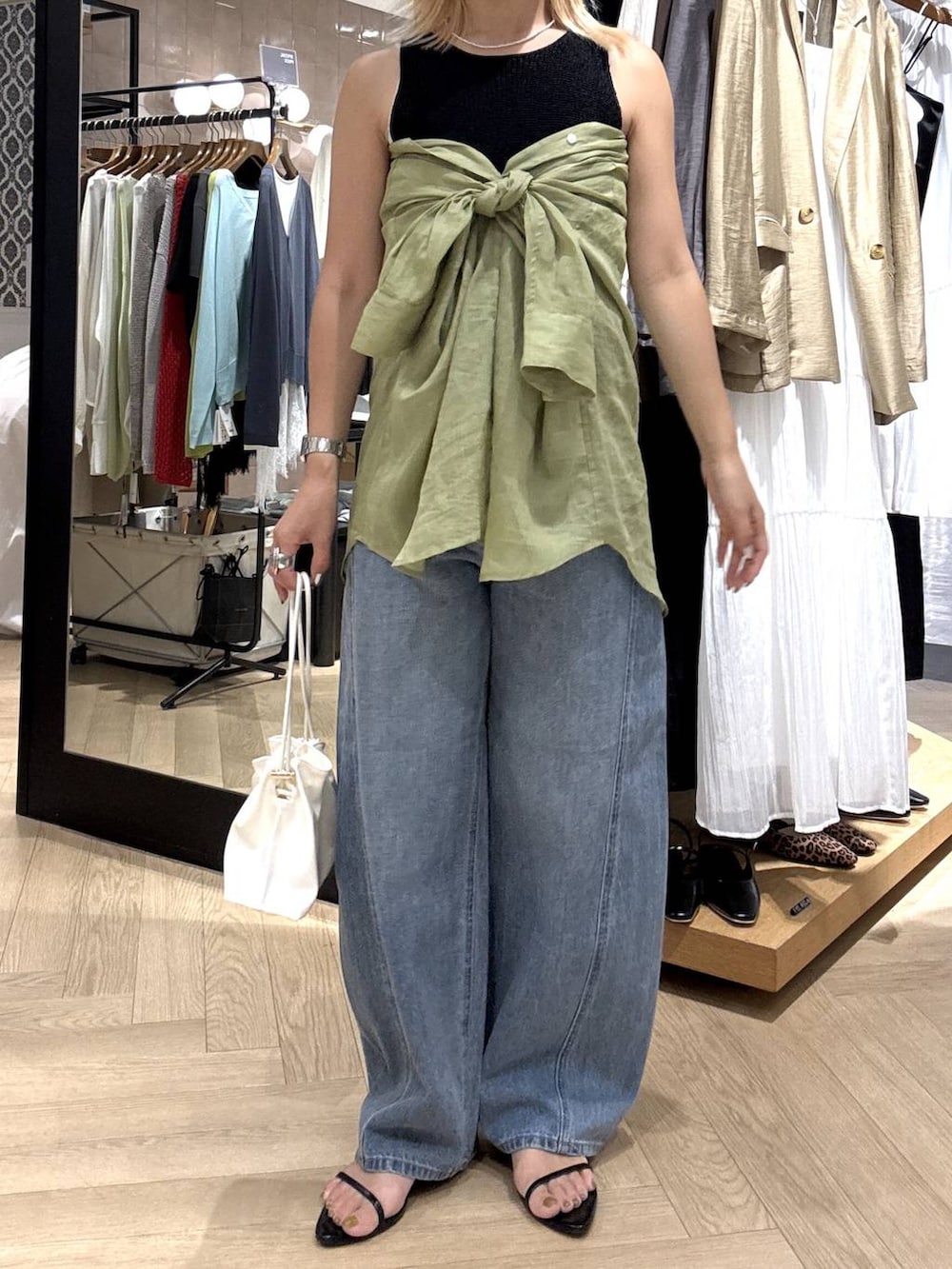 ホワイト系のショルダーバッグ、ブルー系のデニムパンツ、ブラック系のサンダルを着用したレディースの夏コーディネートの3枚目の写真