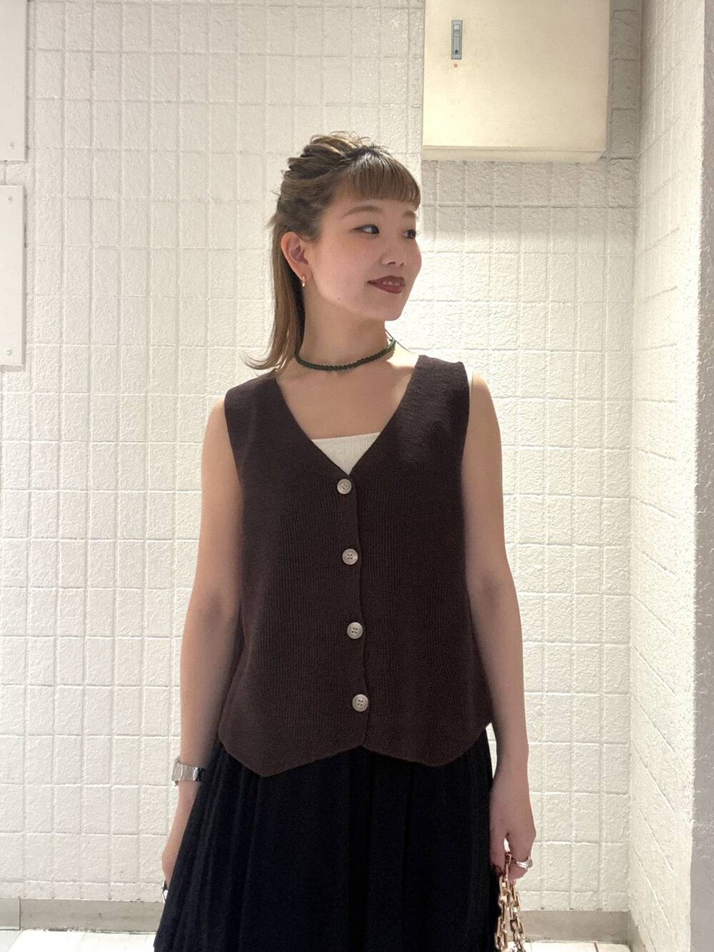 ベージュ系のショルダーバッグ、ブラウン系のベスト、レッド系のサンダルを着用したレディースの春コーディネートの6枚目の写真