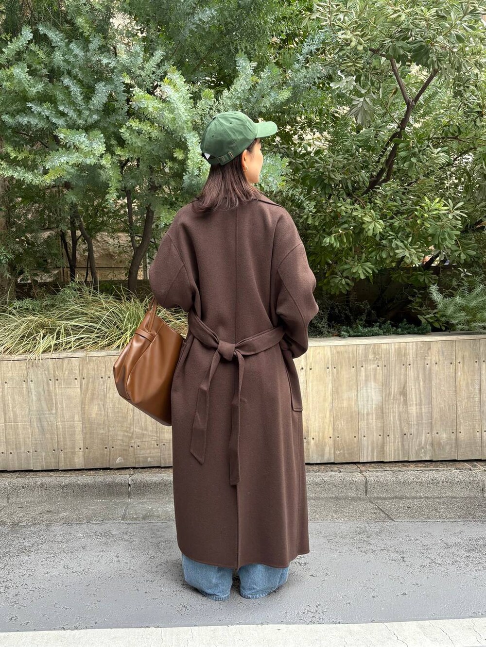 ブラウン系のステンカラーコート、ブルー系のデニムパンツ、ホワイト系のシャツ/ブラウスを着用したレディースの秋コーディネートの3枚目の写真