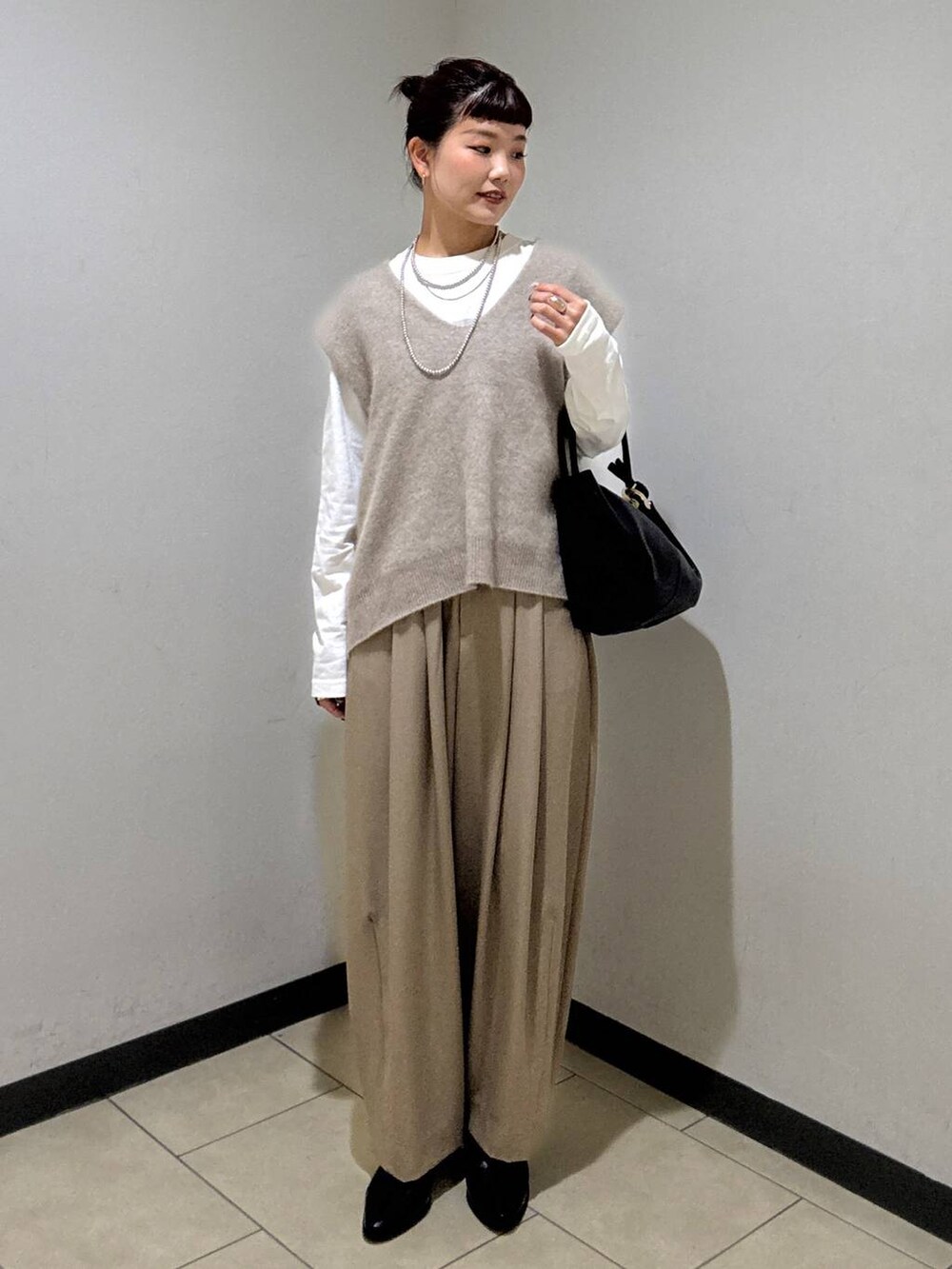 ベージュ系のスラックス、ブラック系のブーツ、ホワイト系のTシャツ/カットソーを着用したレディースの秋コーディネートの5枚目の写真