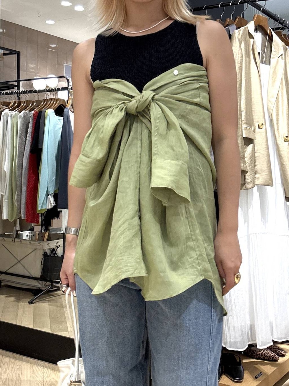 ホワイト系のショルダーバッグ、ブルー系のデニムパンツ、ブラック系のサンダルを着用したレディースの夏コーディネートの2枚目の写真