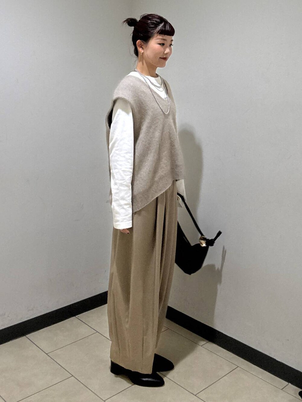 ベージュ系のスラックス、ブラック系のブーツ、ホワイト系のTシャツ/カットソーを着用したレディースの秋コーディネートの3枚目の写真