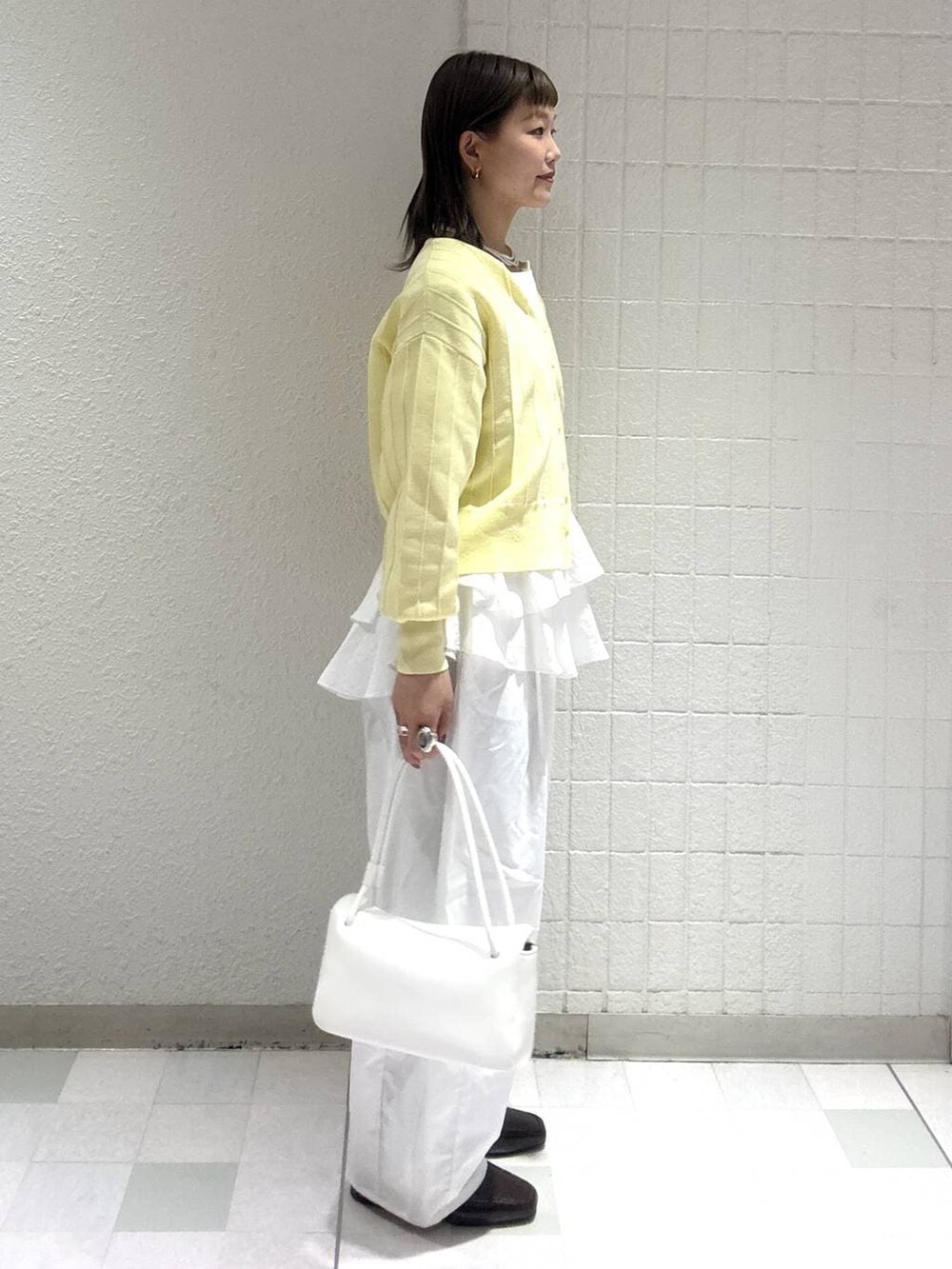 イエロー系のカーディガン/ボレロ、ホワイト系のシャツ/ブラウス、ホワイト系のショルダーバッグを着用したレディースの春コーディネートの2枚目の写真