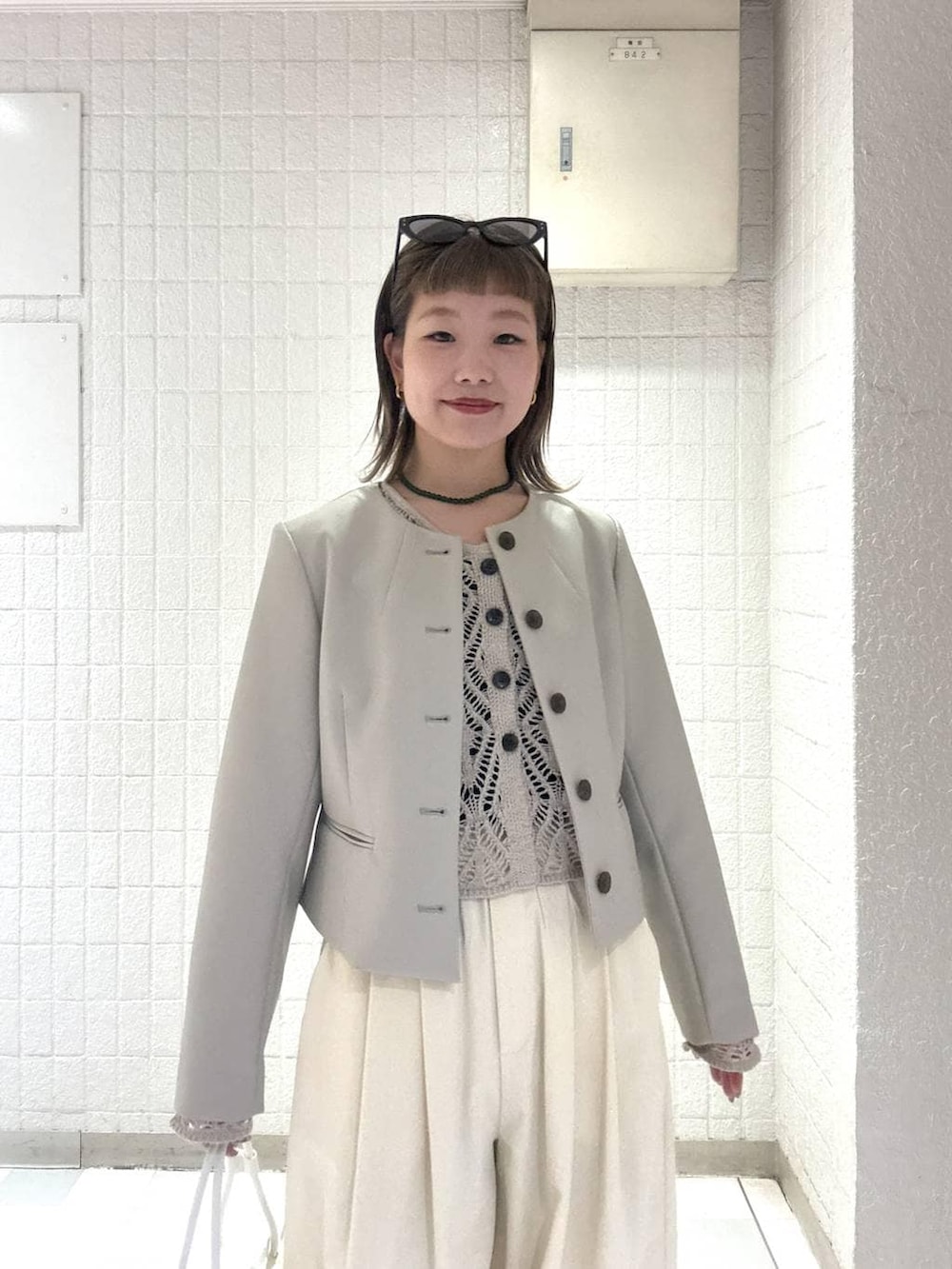 ホワイト系のショルダーバッグ、ベージュ系のカーディガン/ボレロ、ベージュ系のノーカラージャケットを着用したレディースの春コーディネートの6枚目の写真