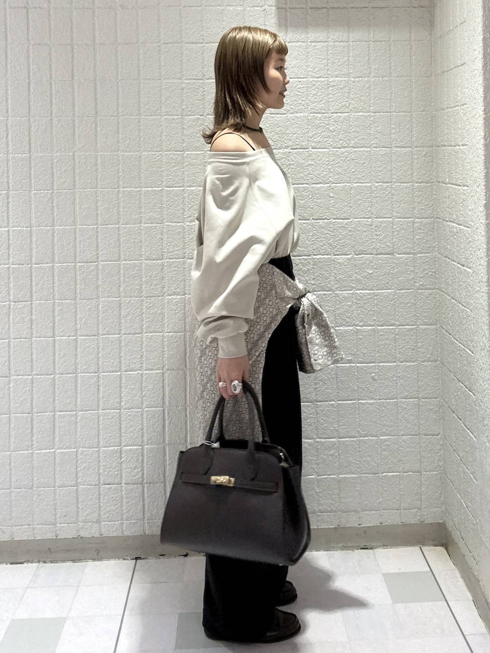 ブラック系のスラックス、ブラウン系のショルダーバッグ、ホワイト系のTシャツ/カットソーを着用したレディースの春コーディネートの3枚目の写真