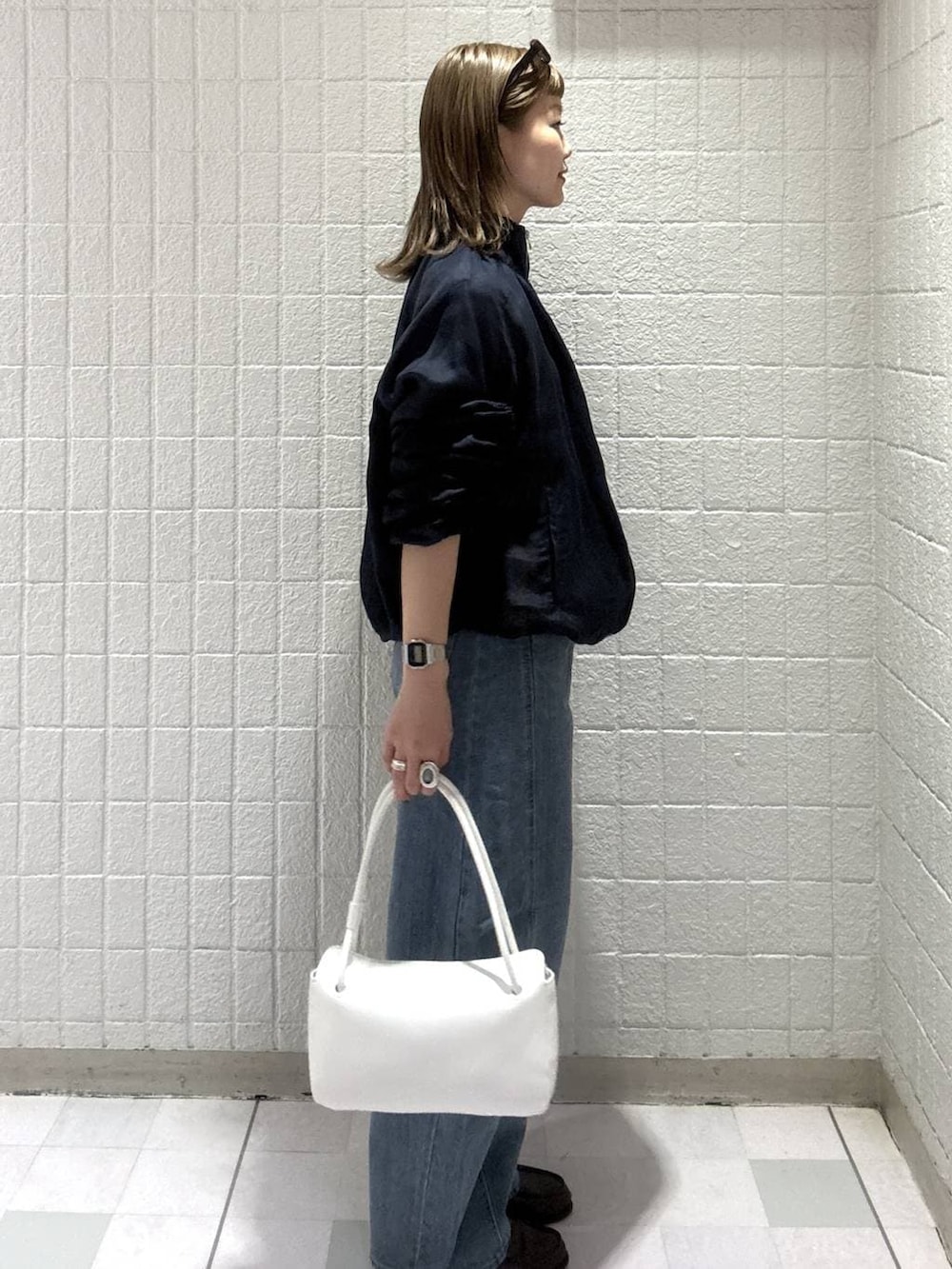 ブルー系のデニムパンツ、ホワイト系のショルダーバッグ、ブルー系のブルゾンを着用したレディースの春コーディネートの3枚目の写真