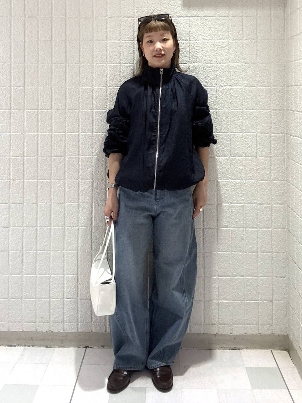 ブルー系のデニムパンツ、ホワイト系のショルダーバッグ、ブルー系のブルゾンを着用したレディースの春コーディネートの2枚目の写真