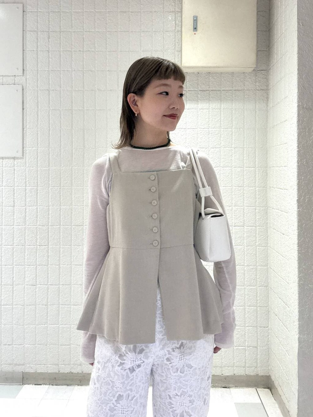 ベージュ系のベスト、ホワイト系のTシャツ/カットソー、ホワイト系のショルダーバッグを着用したレディースの春コーディネートの6枚目の写真